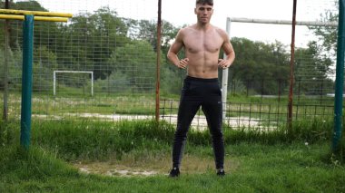 Spor sahasında çömelme hareketleri yapan erkek üstsüz atlet. Yaz doğasında çalışan genç bir sporcu. Güçlü sporcu dışarıda egzersiz yapıyor. Aktif ve sportif yaşam tarzı kavramı. Yavaş çekim