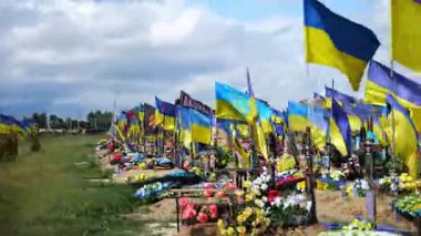 View from window of moving automobile on large military cemetery in Kharkiv with countless graves marked by Ukrainian flags. The site commemorates soldiers who died during russian invasion in Ukraine.