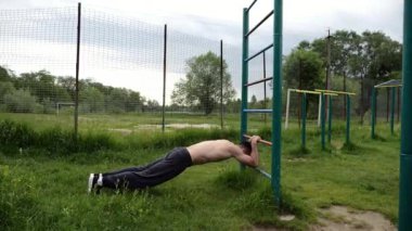 Spor malzemelerinde trisepsler üzerinde egzersiz yapan genç kaslı bir atlet. Spor sahasında spor yapan erkek üstsüz sporcu. Doğada güçlü bir sporcu eğitimi. Sağlıklı yaşam tarzı kavramı.