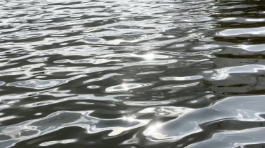 Yazın güneşle aydınlatılan göletin manzara yüzeyi. Güneşli bir günde deniz manzarası ve küçük dalgalar. Güzel yaz doğa manzarası. Huzur sahnesi kavramı. Yavaş çekim