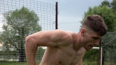 Erkek üstsüz sporcu doğada paralel barlarda şınav çekiyor. Spor alanında egzersiz yapan güçlü bir sporcu. Genç sporcu dışarıda sıkı çalışıyor. Aktif spor yaşam tarzı kavramı. Yavaş çekim
