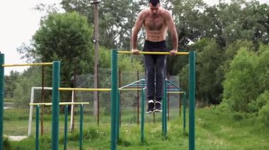 Cesur üstsüz sporcu doğada yatay çıtada şınav çekiyor. Güçlü ve kaslı adam spor alanında antrenman yapıyor. Genç atletik adam dışarıda egzersiz yapıyor. Aktif ve sağlıklı yaşam tarzı kavramı.