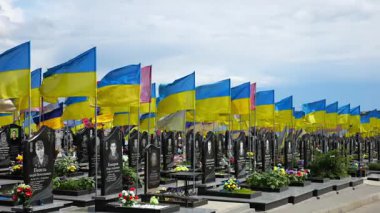 View on countless graves of ukrainian soldiers alley of glory in Kharkiv decorated with waving blue-yellow flags. The site commemorates soldiers who died during russian invasion in Ukraine. Slow motion