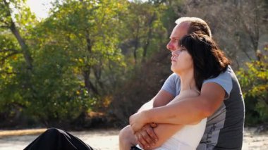 Kumsalda tahta kütüğün üzerinde otururken mutlu çift kucaklaşması. Güneşli bir günde deniz manzarasına hayran olan romantik bir çift. Sevgililer tatil köyünde birlikte vakit geçirirler. Yaz tatili ya da tatil kavramı. Yavaş çekim