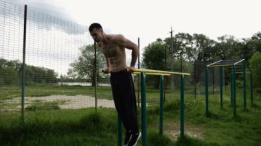 Genç sporcu doğada paralel barlarda şınav çekiyor. Spor alanında egzersiz yapan güçlü bir sporcu. Erkek üstsüz sporcu dışarıda sıkı çalışıyor. Aktif spor yaşam tarzı kavramı. Yavaş çekim
