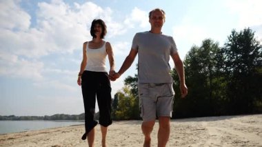 Romantik çift el ele tutuşuyor ve sahilde koşuyor. Güneşli bir günde deniz kıyısında koşan mutlu bir çift. Sevgililer tatil köyünde birlikte vakit geçirirler. Yaz tatili veya tatil kavramı.