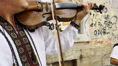 Geleneksel işlemeli vyshyvanka işlemeli yetişkin bir adam şehir caddesinde klasik bir keman çalar. Sahnede kültürel kimlik, miras ve canlı müziğin etkileyici karakteri vurgulanıyor. Yavaş çekim
