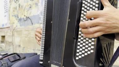 Şehir sokağında akordeon çalan müzisyenin erkek elleri. Detaylı görünüm enstrümanın dokusunu, ritmi, geleneği ve canlı müzik performansının anlamlı karakterini vurgular..