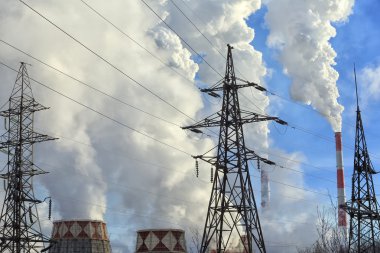 Kışın mavi gökyüzüne karşı bacalardan çıkan sanayi dumanı büyük bitki ve elektrik hatları