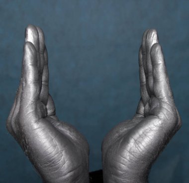 İnsan elinin yakın çekimi, mavi-gri arka planda bir tür kase ya da çiçeği temsil eder.