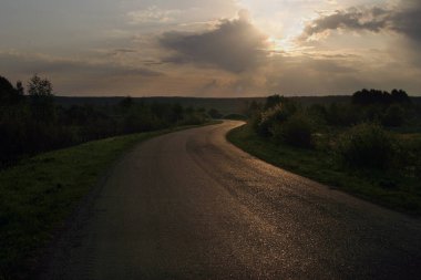 Şafak vakti, sel basmış çayırların ortasında ıssız bir yol boyunca seyahat etmek.