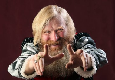 Orta Çağ 'dan kalma uzun sakallı ve bıyıklı bir adamın portresi. Takım elbise giymiş, ellerini sallıyor. Ciddi görünüyor.