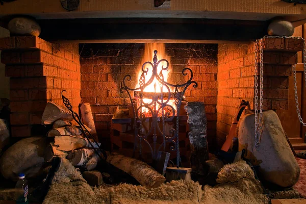 Close-up of brick fireplace with an iron gate with a bright flame burning logs