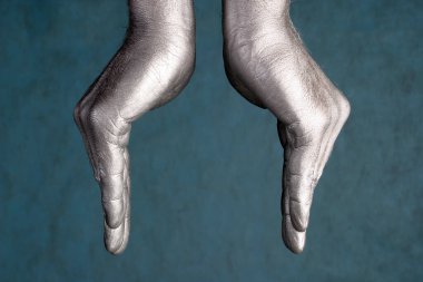 İnsan elinin yakın çekimi, mavi-gri arka planda bir tür kase ya da çiçeği temsil eder.