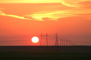 Güzel bir günbatımının arka planında peyzaj elektrik hatları