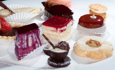 Beyaz tabak stüdyosunda çeşitli pasta ve çikolataların yakın plan çekimi.