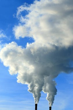 Mavi gökyüzüne karşı bitkinin bacasından izole edilmiş beyaz duman.