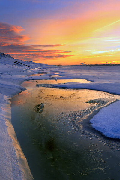 winter landscape sunset on the ice of the river and the city on the horizon