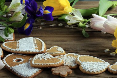  Sarı kurdeleli kalp şeklinde makro zencefilli kurabiye, ahşap arka planda çiçekler.