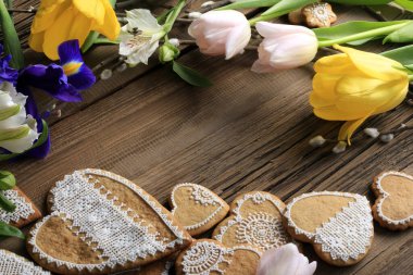  Sarı kurdeleli kalp şeklinde makro zencefilli kurabiye, ahşap arka planda çiçekler.