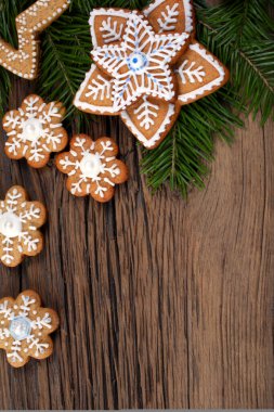 Köknar dallarının yakın çekimleri ve sihirli Noel tatili desenli zencefilli çörekler arka planda bir ahşap tahta stüdyo.