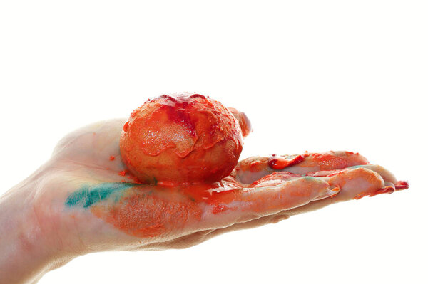 close-up of a single egg in the orange paint in female hands on a light background studio