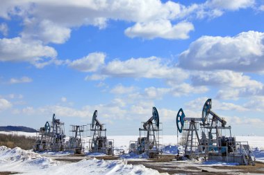 Endüstriyel peyzaj petrol pompaları mavi gökyüzünün arka planında ve güneşli bir bahar sabahında beyaz bulutlarda