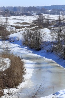 Baharın başlarında, ormanın yakınındaki donmuş nehir manzarası.