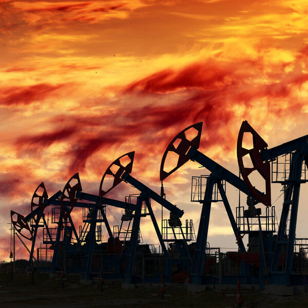 close-up of oil pumps on background of dramatic clouds at sunset