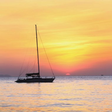 Deniz manzaralı gün batımı ve Tayland kıyılarında sönük yelkenli bir tekne.