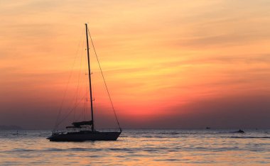 Deniz manzaralı gün batımı ve Tayland kıyılarında sönük yelkenli bir tekne.