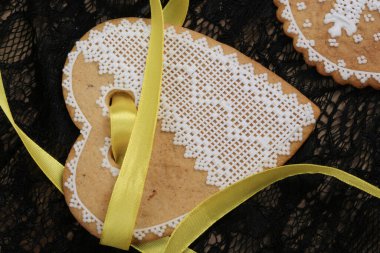 Siyah arka plan stüdyosuna asılmış sarı bantlı kalp şeklinde zencefilli paskalya pastası.