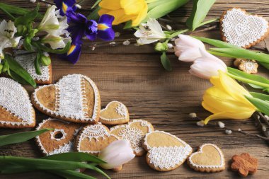  Sarı kurdeleli kalp şeklinde makro zencefilli kurabiye, ahşap arka planda çiçekler.