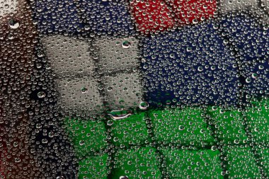 Camdaki su damlacıkları, Rubik Küpü 'nün arka planına yakın çekim.