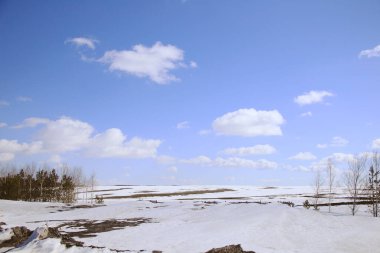 ilkbahar karları erir tarlada ve beyaz bulutlar mavi gökyüzünde güneşli bir günde