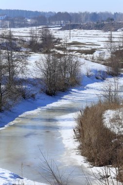 Baharın başlarında, ormanın yakınındaki donmuş nehir manzarası.