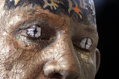 Kil vücut sanatında bir adamın yakın plan portresi, karanlık arka planda stüdyo.