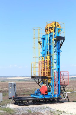 Yazın, güneşli bir günde mavi gökyüzünün arka planındaki tahıl tarlalarına petrol pompalanıyor.