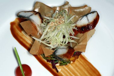 Siyah arka plan stüdyosunda hamurdan yapılmış bir sepetin içinde balık ve sebzeli yakın plan gurme salatası.