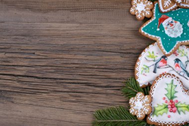 Köknar dallarının yakın çekimleri ve sihirli Noel tatili desenli zencefilli çörekler arka planda bir ahşap tahta stüdyo.