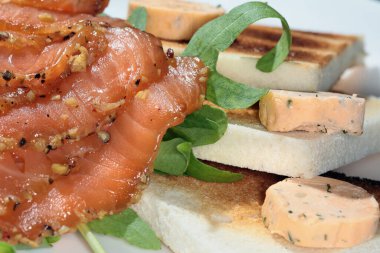 Kızarmış ekmek, füme kırmızı balık ve beyaz tabak stüdyosunda yeşillikler.