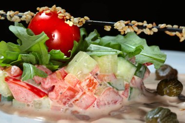 Kapari, taze otlar ve krema sosuyla süslenmiş, siyah bir arka plan stüdyosundaki beyaz tabakta çok güzel dekore edilmiş.