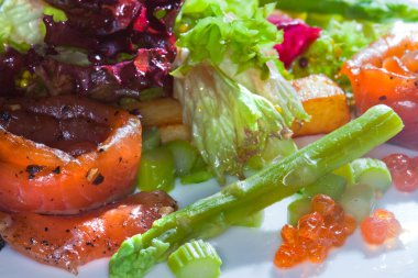 Kırmızı balıklı ve sebzeli yakın plan salata. Beyaz tabakta, arka planda, stüdyoda.