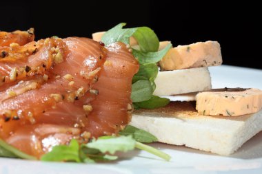 Kızarmış ekmek, füme kırmızı balık ve beyaz tabak stüdyosunda yeşillikler.