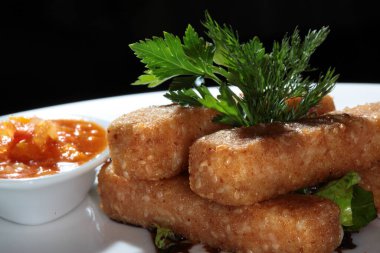 Balık kroketi, sebzeli ve soslu beyaz tabakta.