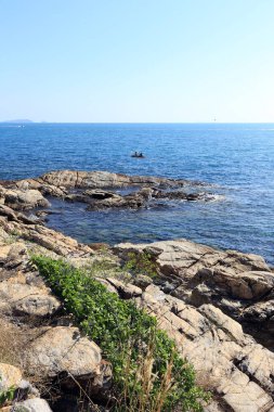 Güneşli bir günde Tayland açıklarında deniz manzaralı kayalık kıyı ve mavi su