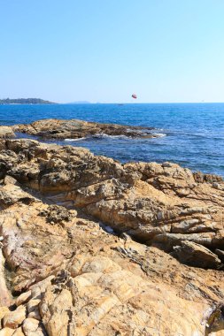Güneşli bir günde Tayland açıklarında deniz manzaralı kayalık kıyı ve mavi su