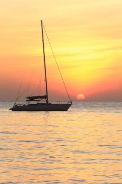 Deniz manzaralı gün batımı ve Tayland kıyılarında sönük yelkenli bir tekne.