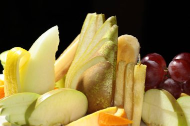 Siyah arka plan stüdyosunda beyaz tabakta güzel bir meyve salatası.