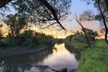 Yaz manzarası güzel, parlak gün batımı nehir ve ufukta meşe ormanı.